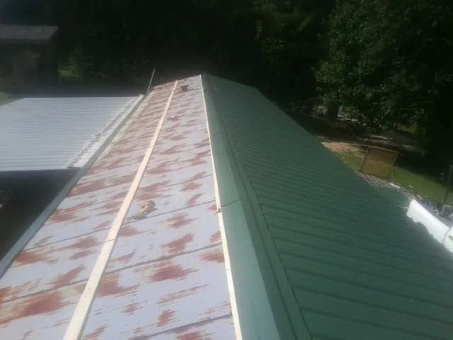 Old rusted panels beside newly installed green metal roofing — Wind Damage Roof Repair by Roofing Brothers in Dow City