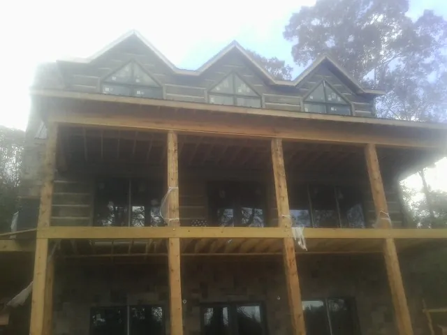 Dormers and porch framing on a large log home under construction — Roof Coating work by our crew in Dow City
