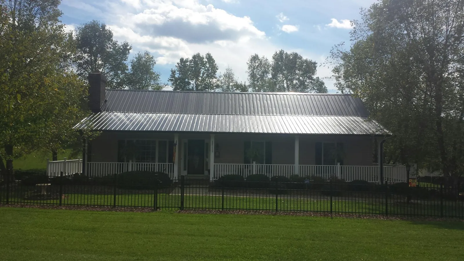 Gray metal roof on a brick ranch with a full width front porch — Gutter Guard Installation work by our crew in Dow City