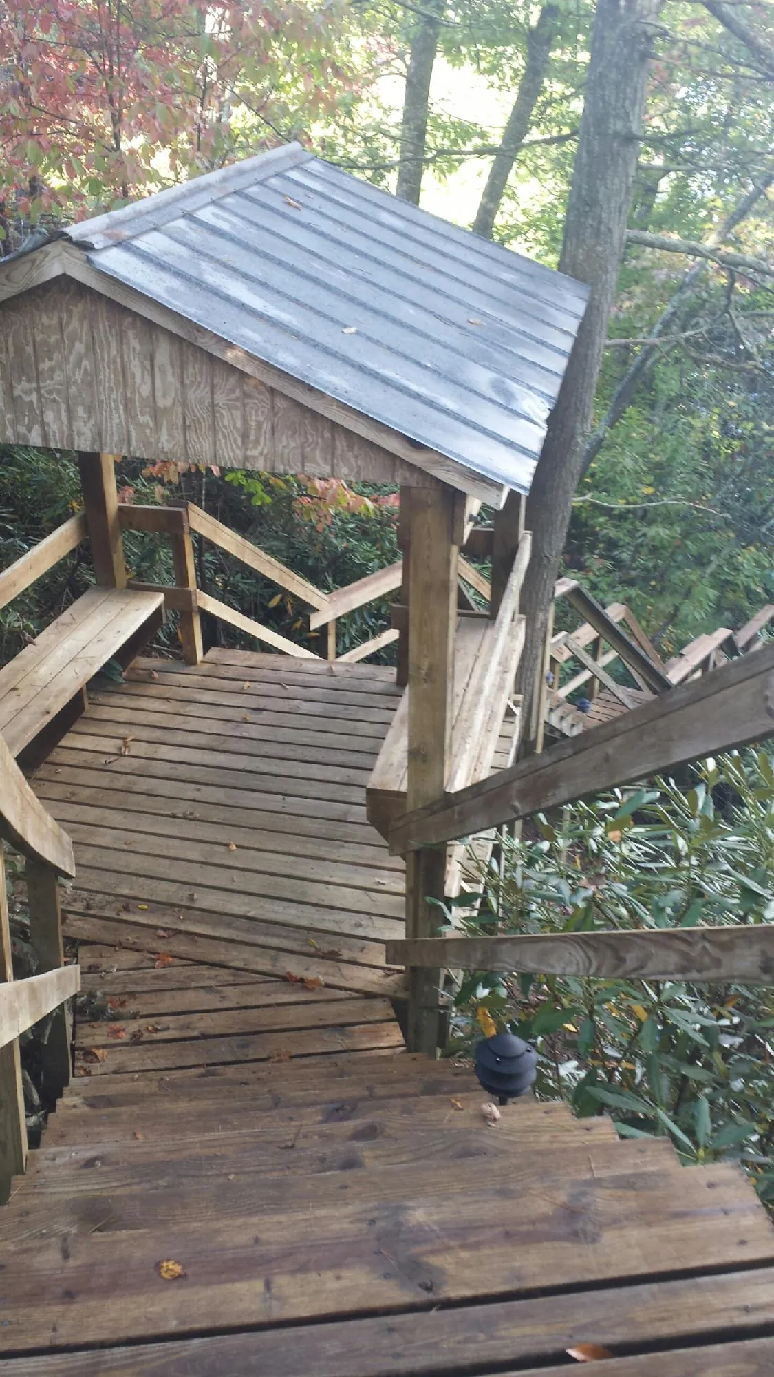 Metal roofed shelter over wooden steps on a wooded walkway — Skylight Repair & Installation work by our crew in Dow City