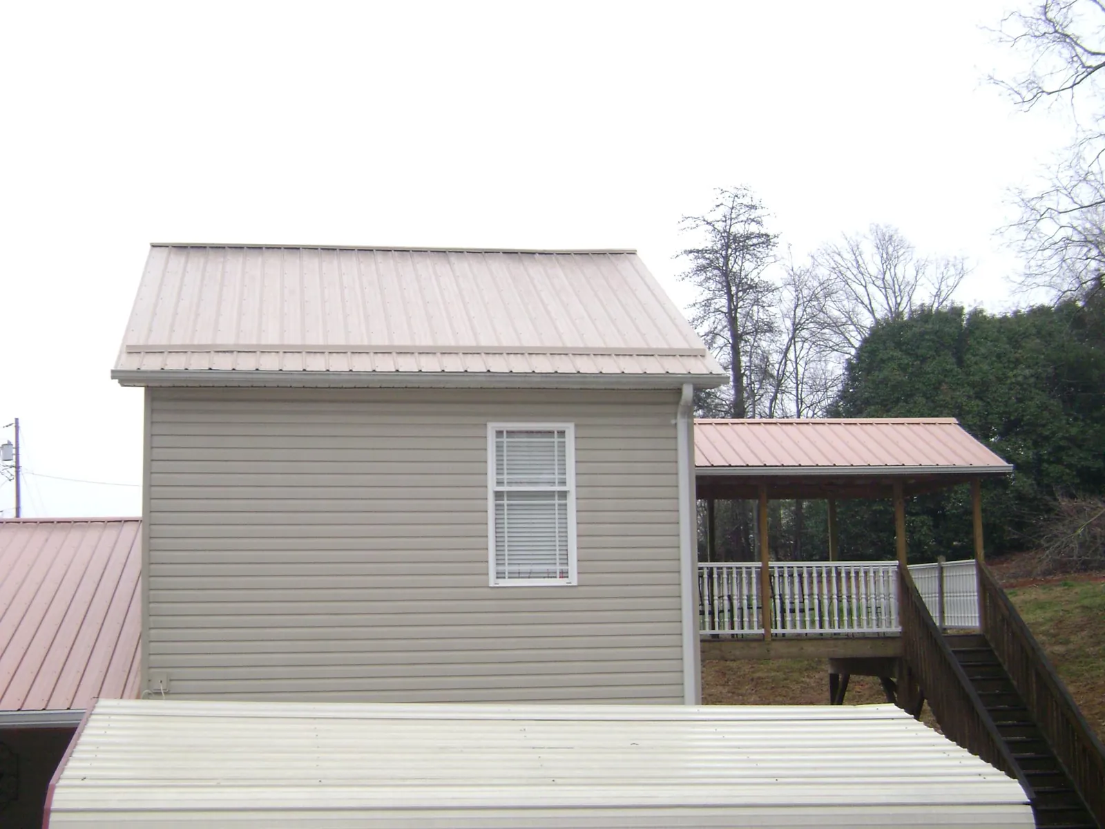 Tan metal roofs on a two story addition and attached porch, from a Roof Replacement job in Dow City